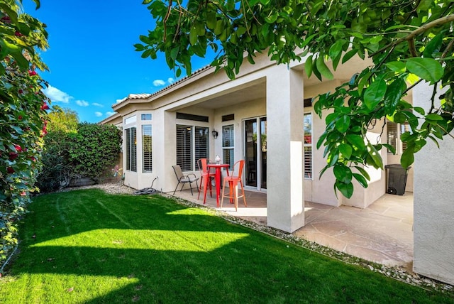 rear view of property featuring a lawn and a patio area