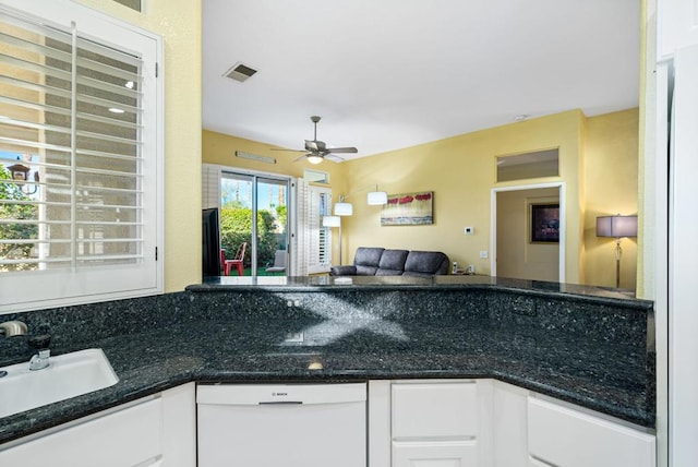 kitchen with dark stone counters, white dishwasher, sink, ceiling fan, and white cabinetry