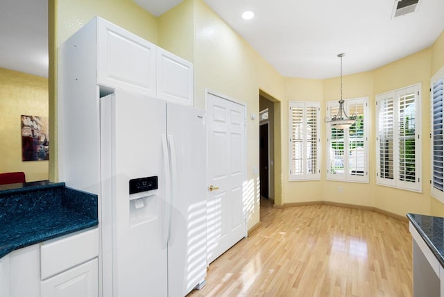 kitchen with white cabinetry, white refrigerator with ice dispenser, hanging light fixtures, and light hardwood / wood-style flooring