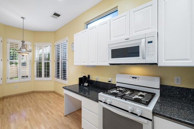 kitchen featuring white appliances, white cabinets, light hardwood / wood-style flooring, dark stone countertops, and decorative light fixtures