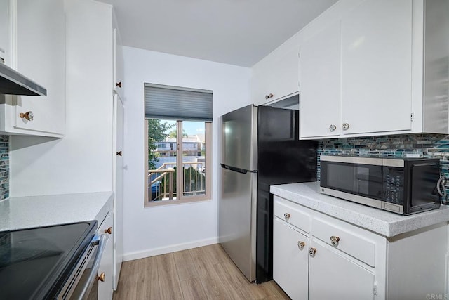 kitchen with exhaust hood, light hardwood / wood-style flooring, decorative backsplash, appliances with stainless steel finishes, and white cabinetry