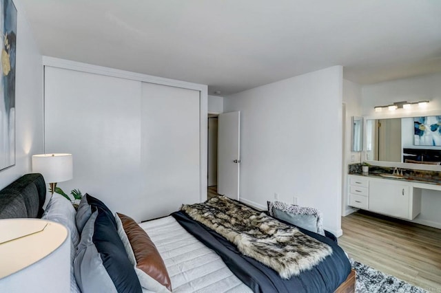 bedroom with a closet, sink, and light hardwood / wood-style flooring