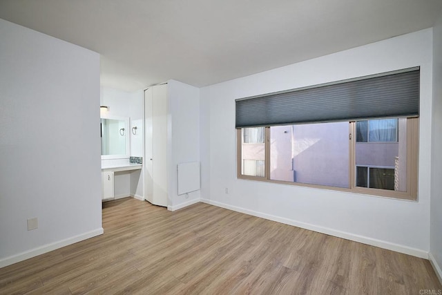 unfurnished bedroom with ensuite bath and light wood-type flooring