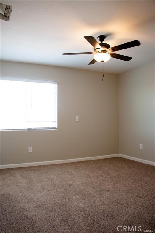 carpeted empty room featuring ceiling fan