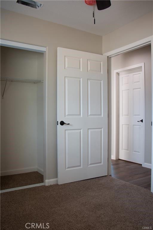 unfurnished bedroom with ceiling fan, dark hardwood / wood-style flooring, and a closet