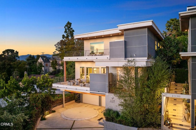 back house at dusk featuring a balcony