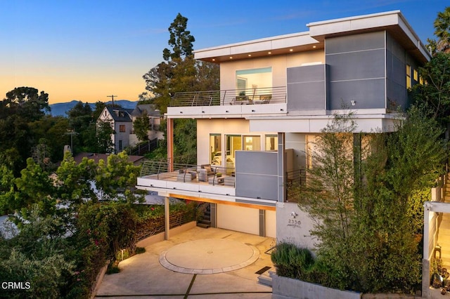 back house at dusk with a balcony