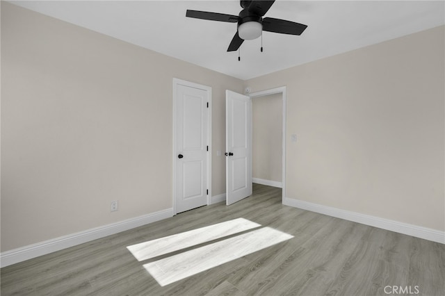 unfurnished bedroom with ceiling fan, light wood-type flooring, and a closet