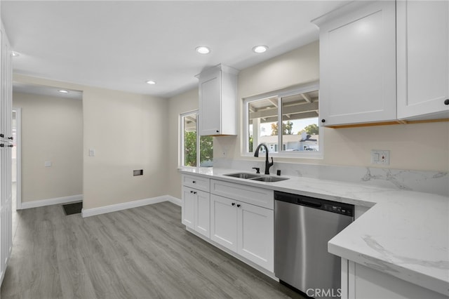 kitchen with light stone countertops, dishwasher, white cabinets, and sink