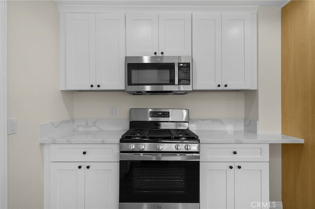 kitchen with light stone countertops, white cabinets, and appliances with stainless steel finishes