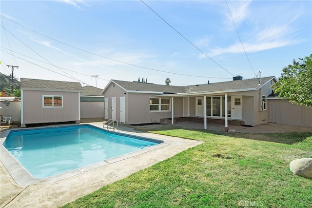 rear view of house featuring a fenced in pool, a yard, a patio, and an outdoor structure