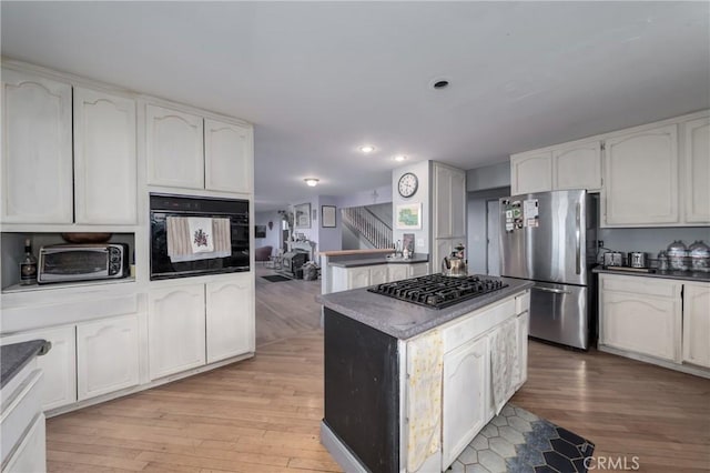 kitchen with a kitchen island, stainless steel appliances, white cabinets, and light hardwood / wood-style flooring