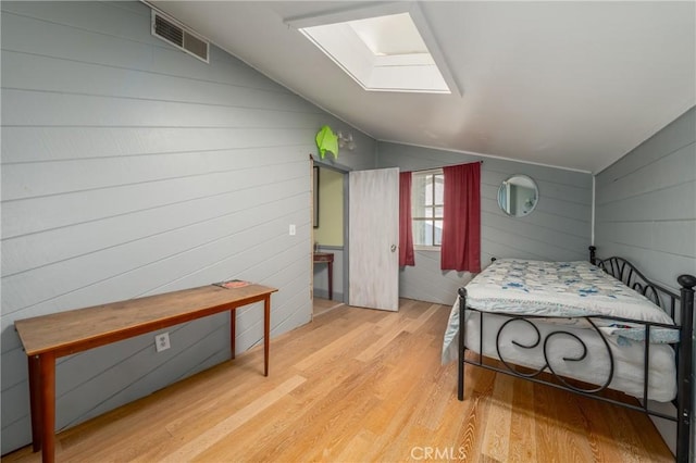 bedroom with vaulted ceiling with skylight and light wood-type flooring