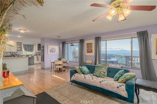 living room with light hardwood / wood-style floors, ceiling fan, and a mountain view