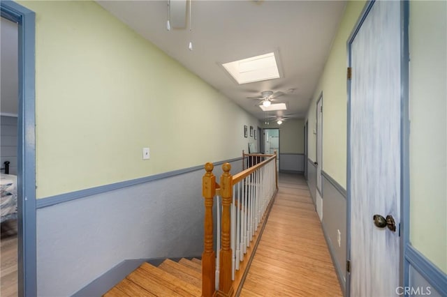 hall with light wood-type flooring and a skylight