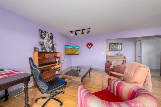 sitting room with light wood-type flooring and rail lighting