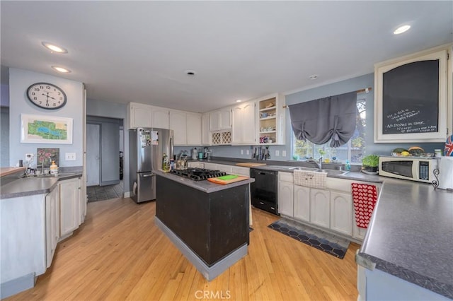 kitchen featuring light hardwood / wood-style flooring, sink, white cabinetry, a kitchen island, and black appliances