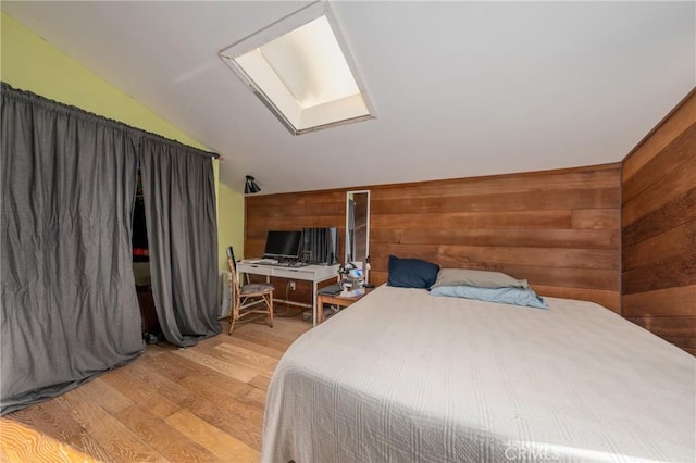 bedroom featuring light hardwood / wood-style flooring, wooden walls, and lofted ceiling