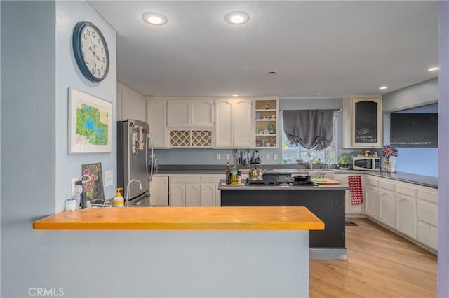 kitchen featuring butcher block countertops, a kitchen island, light hardwood / wood-style floors, appliances with stainless steel finishes, and white cabinets