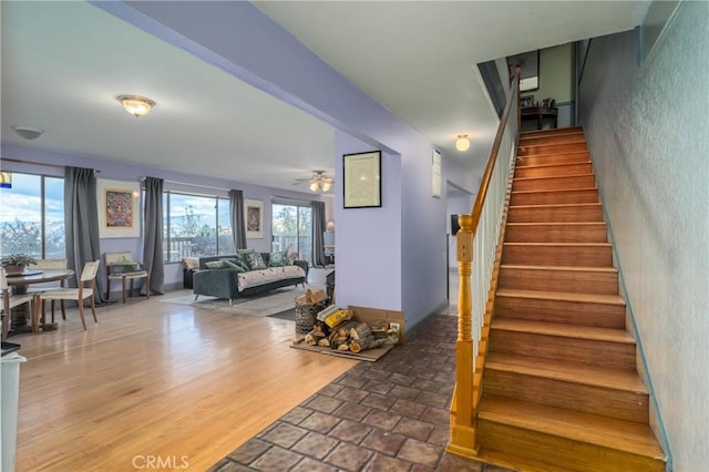 stairs with hardwood / wood-style floors and ceiling fan