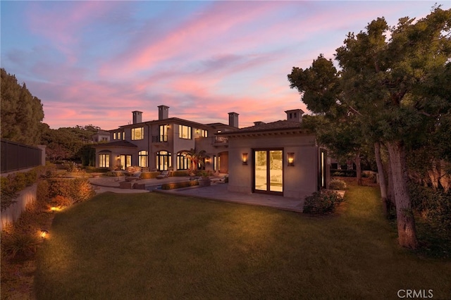 back house at dusk with a yard and a patio area