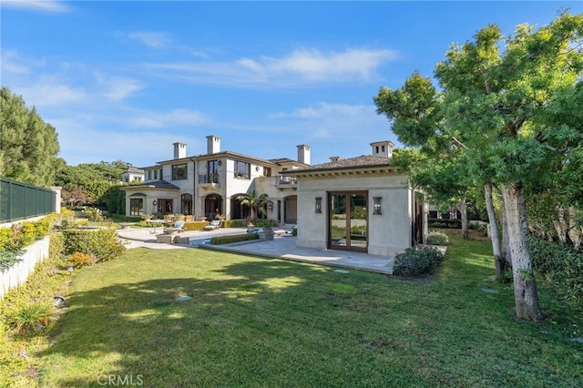 rear view of house with a yard, french doors, a balcony, and a patio