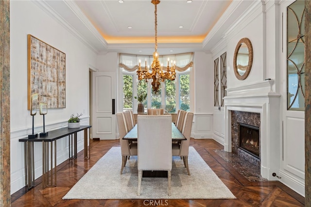 dining area with a tray ceiling, dark parquet flooring, and a premium fireplace