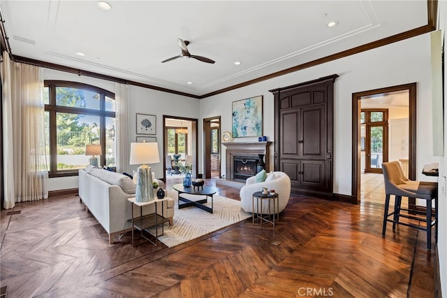 living room featuring dark parquet floors, ceiling fan, and crown molding