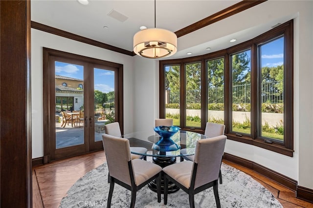 dining room featuring plenty of natural light, light hardwood / wood-style floors, crown molding, and french doors