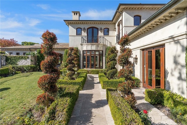 view of front of property featuring a balcony, a front yard, and french doors