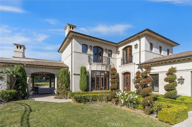 view of front of home featuring a patio area, ceiling fan, a balcony, and a front yard