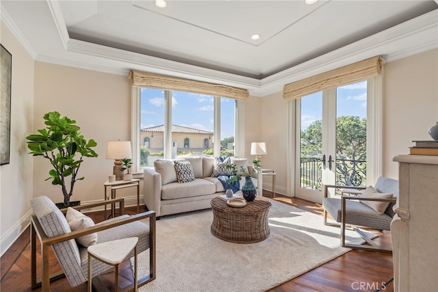 sitting room with wood-type flooring, a tray ceiling, french doors, and ornamental molding