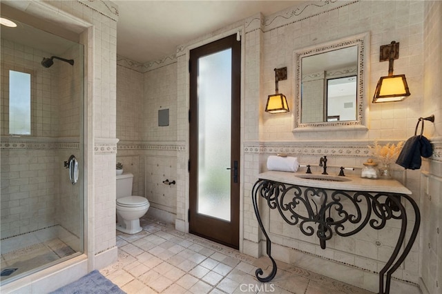 bathroom featuring tile patterned flooring, toilet, a shower with door, and tile walls