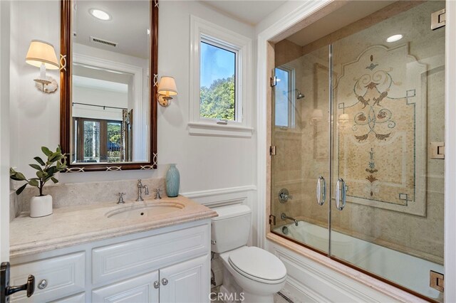 full bathroom featuring bath / shower combo with glass door, vanity, a healthy amount of sunlight, and toilet