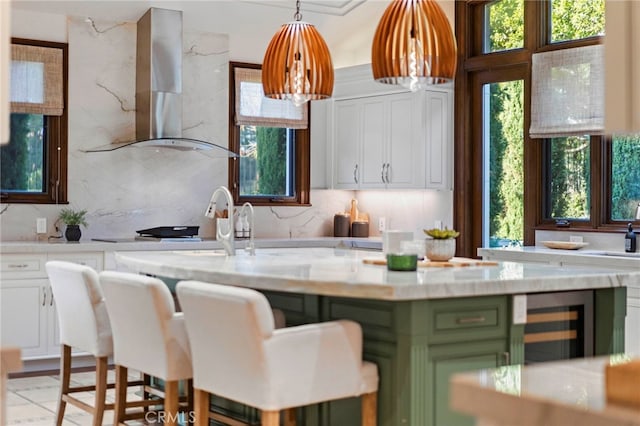 7 Shoreview, Newport Coast, CA 92657 - kitchen with wall chimney range hood, green cabinetry, wine cooler, white cabinetry, and decorative light fixtures
