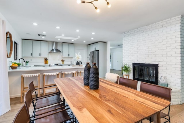 dining area with a fireplace, light wood-type flooring, and sink