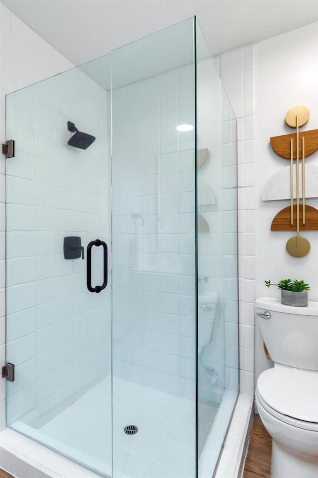 bathroom featuring toilet, wood-type flooring, and walk in shower