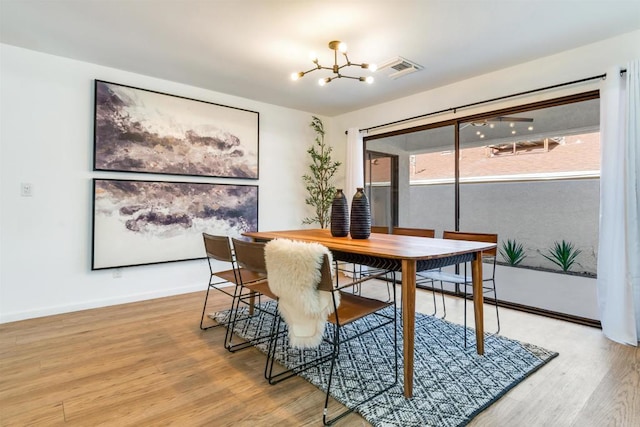 dining area with light hardwood / wood-style floors and an inviting chandelier