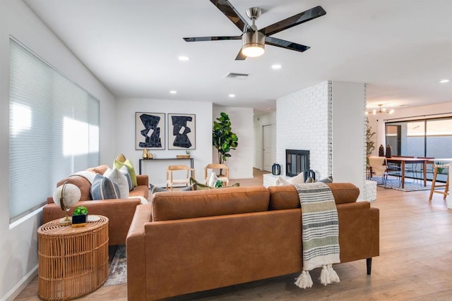 living room with ceiling fan, a fireplace, and light wood-type flooring