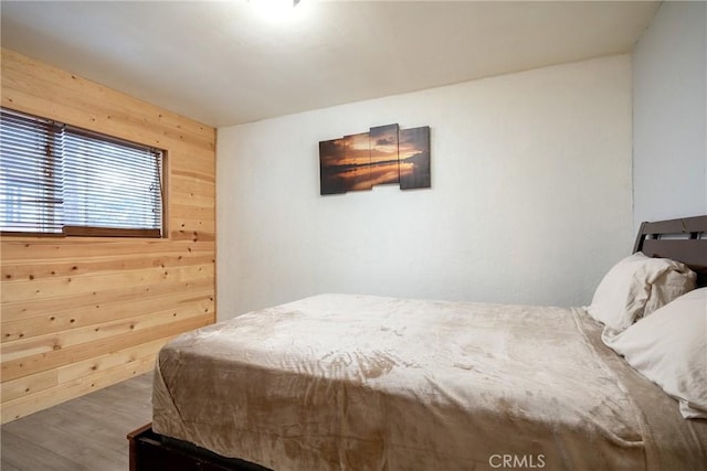 bedroom with wood walls and hardwood / wood-style flooring