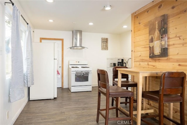 kitchen featuring white appliances, dark wood-type flooring, and wall chimney range hood