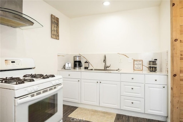 kitchen with white cabinets, sink, dark hardwood / wood-style flooring, white range with gas stovetop, and extractor fan