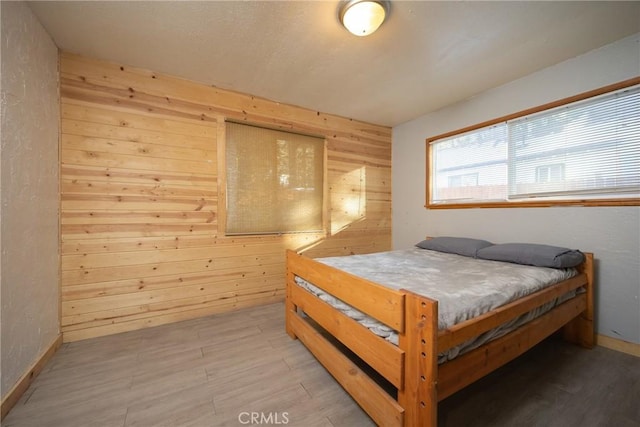 bedroom featuring wooden walls and light hardwood / wood-style floors