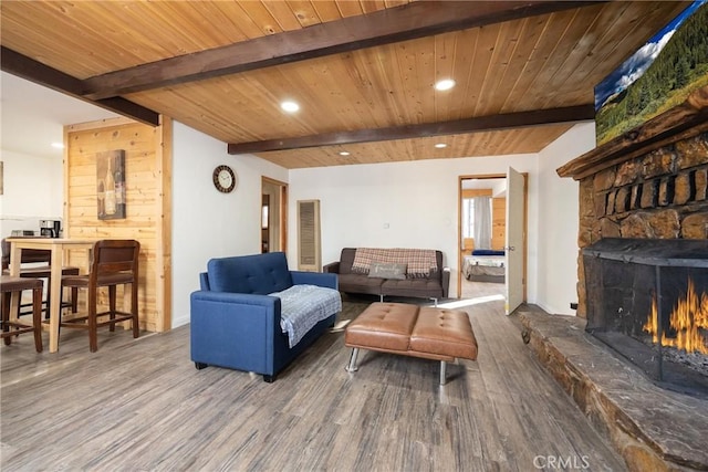 living room featuring beam ceiling, a stone fireplace, wood-type flooring, and wooden ceiling