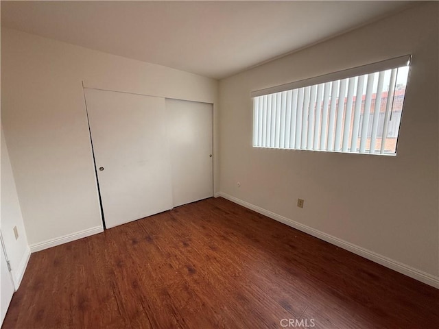 unfurnished bedroom featuring dark hardwood / wood-style flooring and a closet