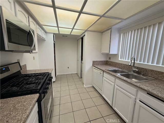 kitchen with sink, white cabinets, light tile patterned floors, and appliances with stainless steel finishes