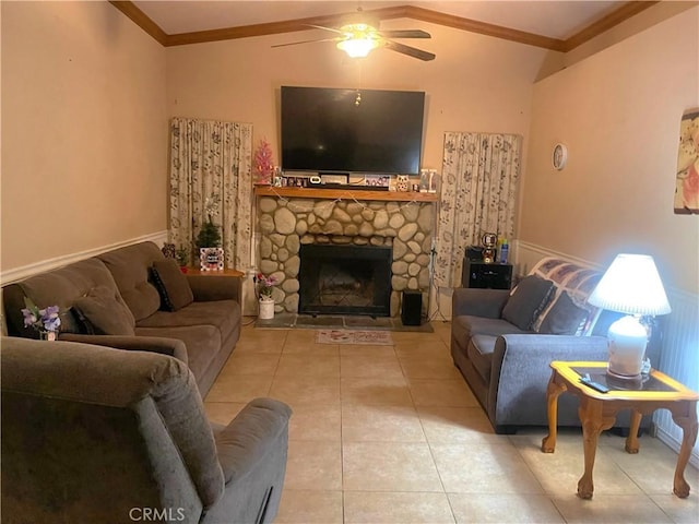 tiled living room with vaulted ceiling, ceiling fan, ornamental molding, and a stone fireplace