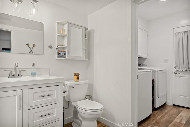 bathroom featuring toilet, vanity, wood finished floors, and independent washer and dryer