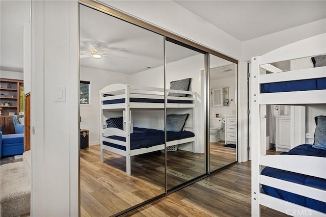 bedroom featuring a closet, ensuite bath, and wood finished floors