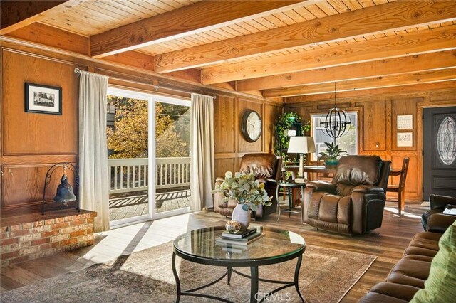 living room featuring beamed ceiling, a notable chandelier, hardwood / wood-style floors, wooden walls, and wood ceiling